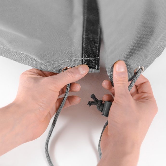 Hands fitting a protective cover on a serviced patio heater